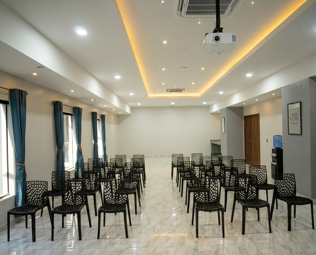 Event room at Los Olivos Hotel with chairs, projector and screen